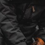 Survival Instincts - A person in a parka and gloves is cutting wood