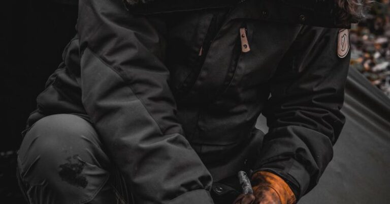 Survival Instincts - A person in a parka and gloves is cutting wood