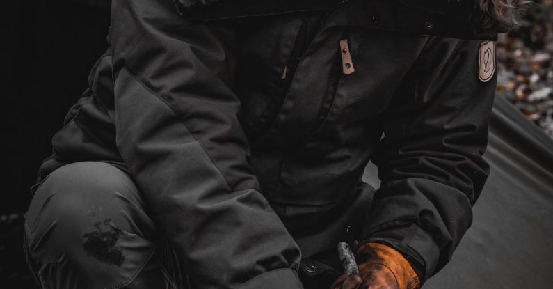 Survival Instincts - A person in a parka and gloves is cutting wood