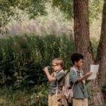 Orienteering - Boys Standing on Grass Field Near Brown Tree