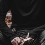 Survival Mistakes - A man sitting in the woods with a knife